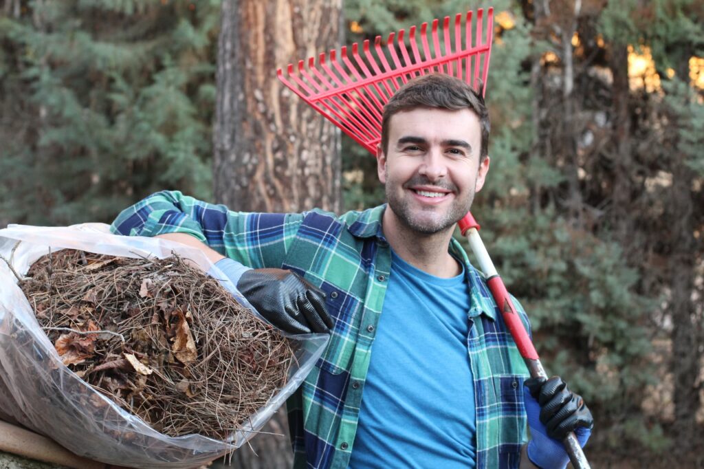 a landscaper holding a rake and a bag of leaves